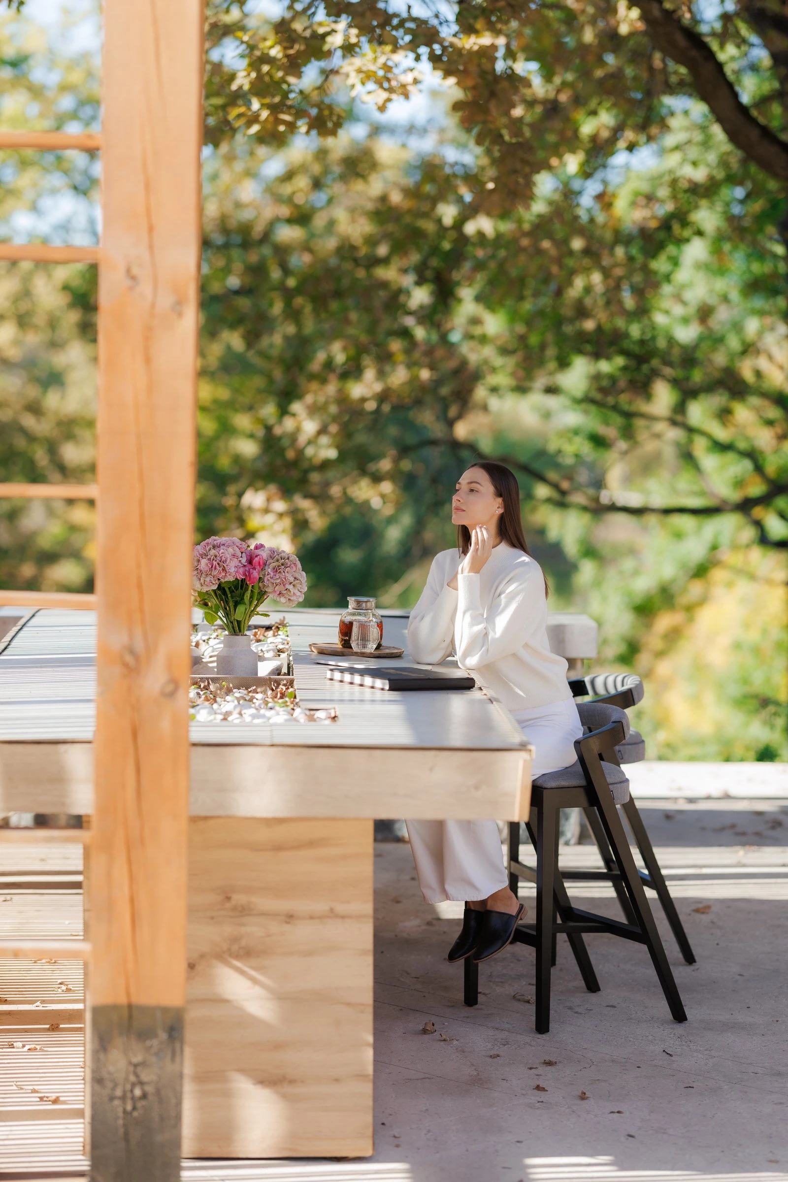 Model in cream seated at the villa stone counter with Baffi bar stools and hydrangeas