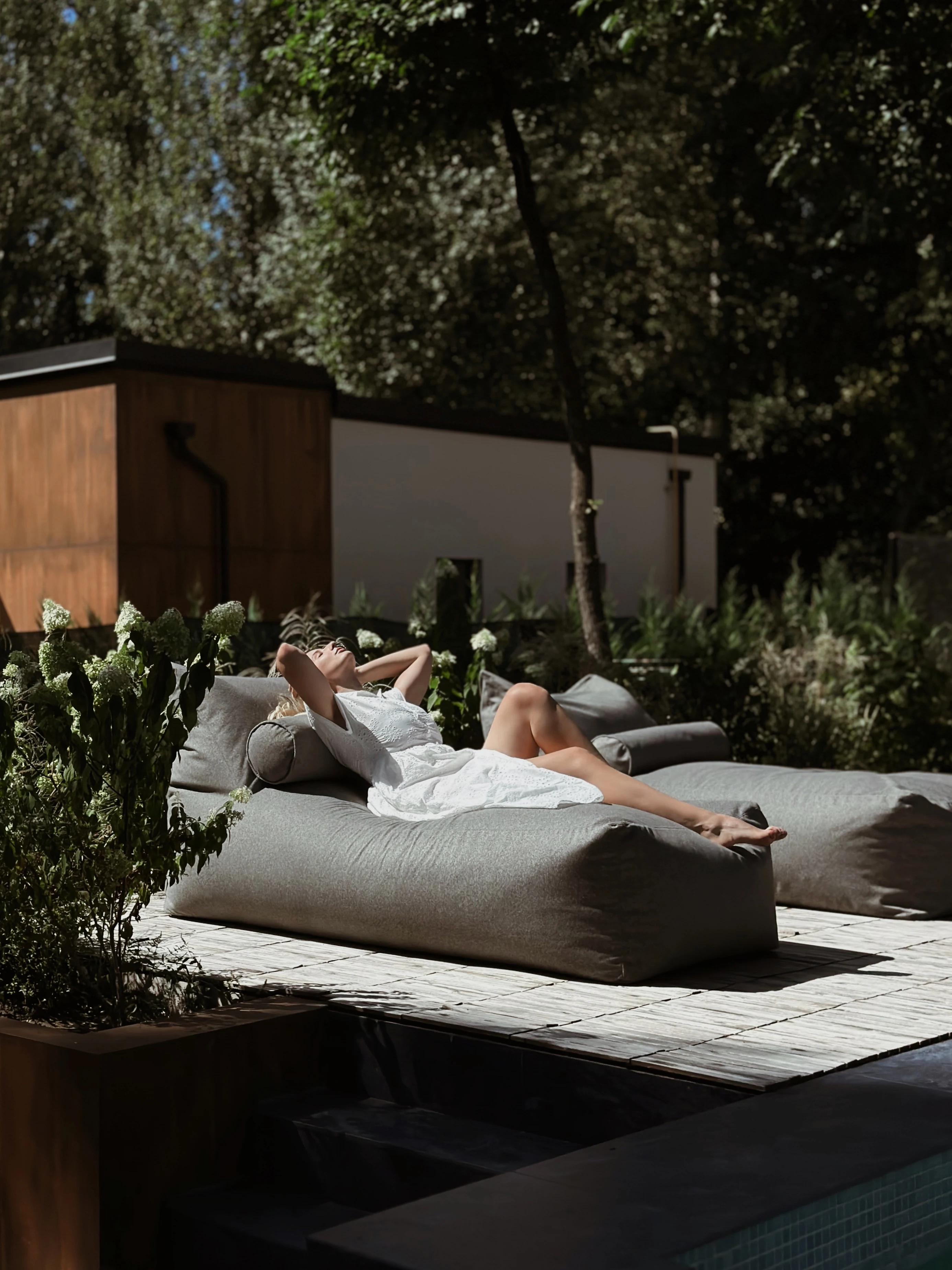 Woman reclining on a deep-grey Marolla lounger beside a villa pool
