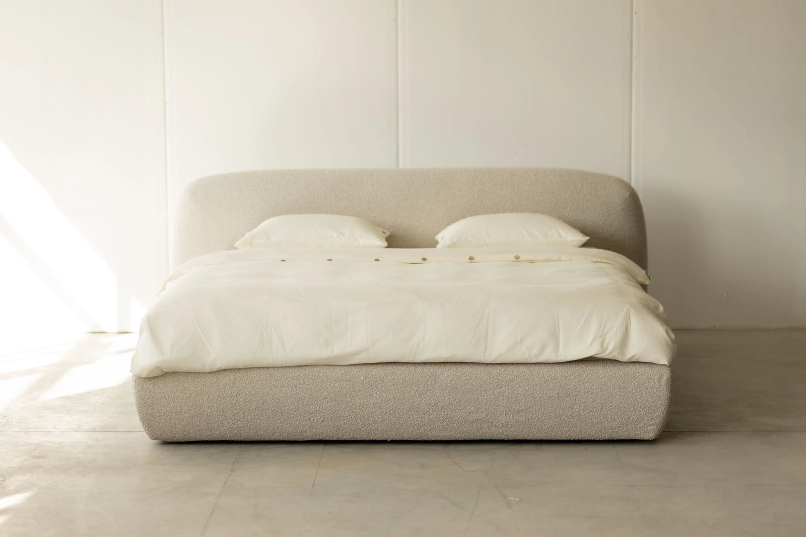 Cream boucle Belagio centered against a white panel-board wall, clean studio light