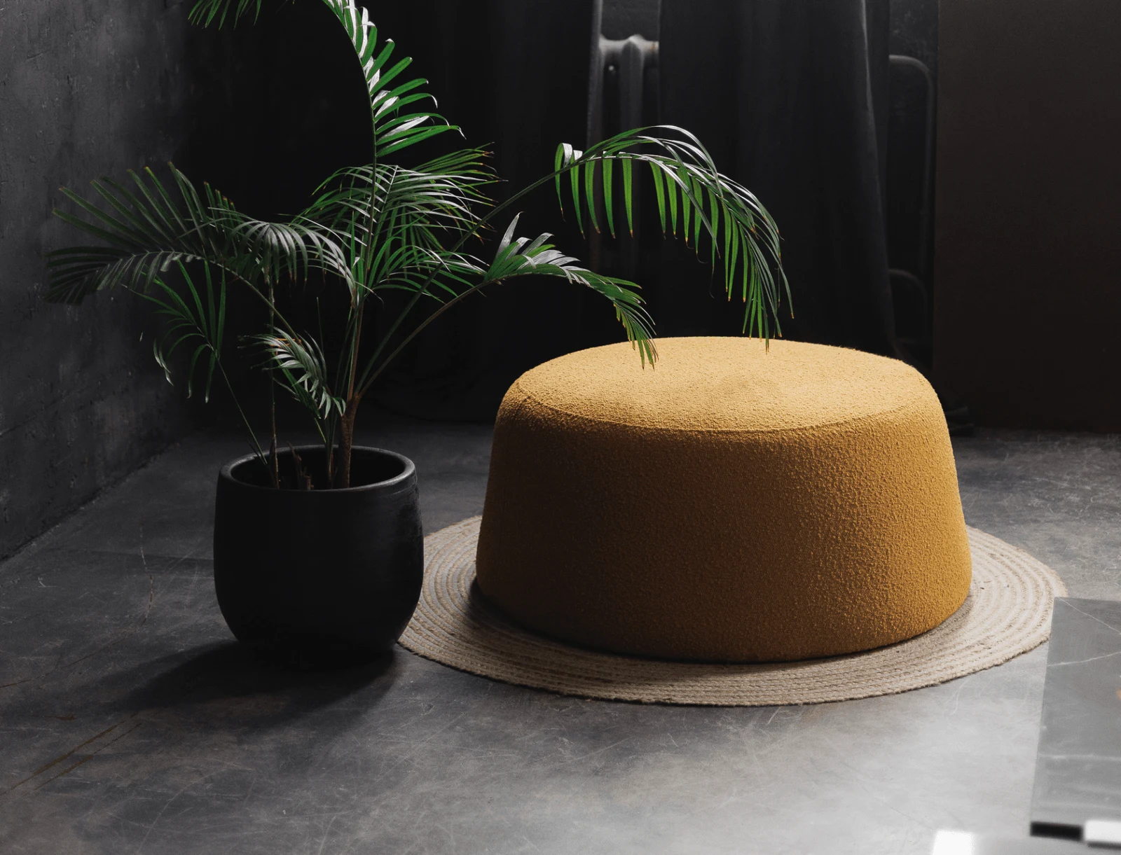 Mustard Copenhaghen 400 bouclé Macarons pouf beside a palm in a dark room