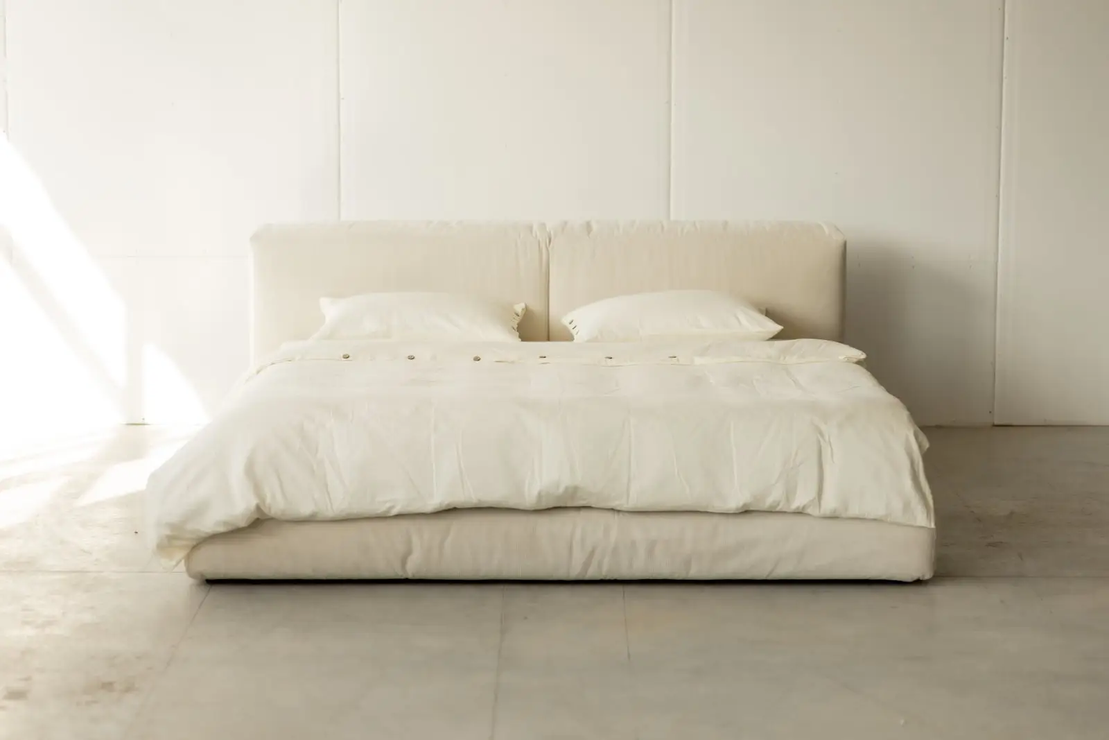 Cream Marmaris in a bright minimal studio with full white bedding and panel walls behind