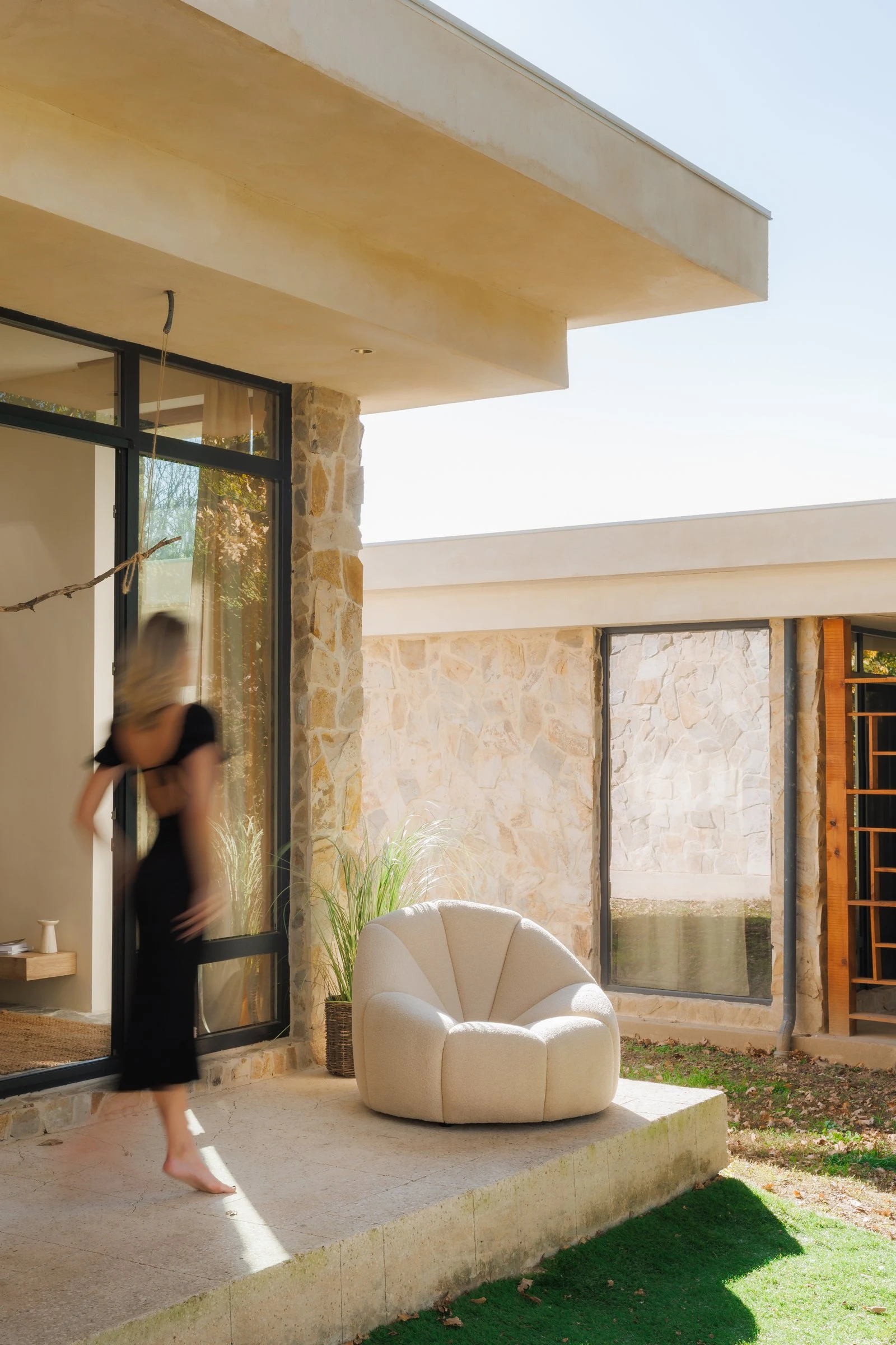 Three-quarter view of the Flora chair on the villa patio with autumn trees beyond