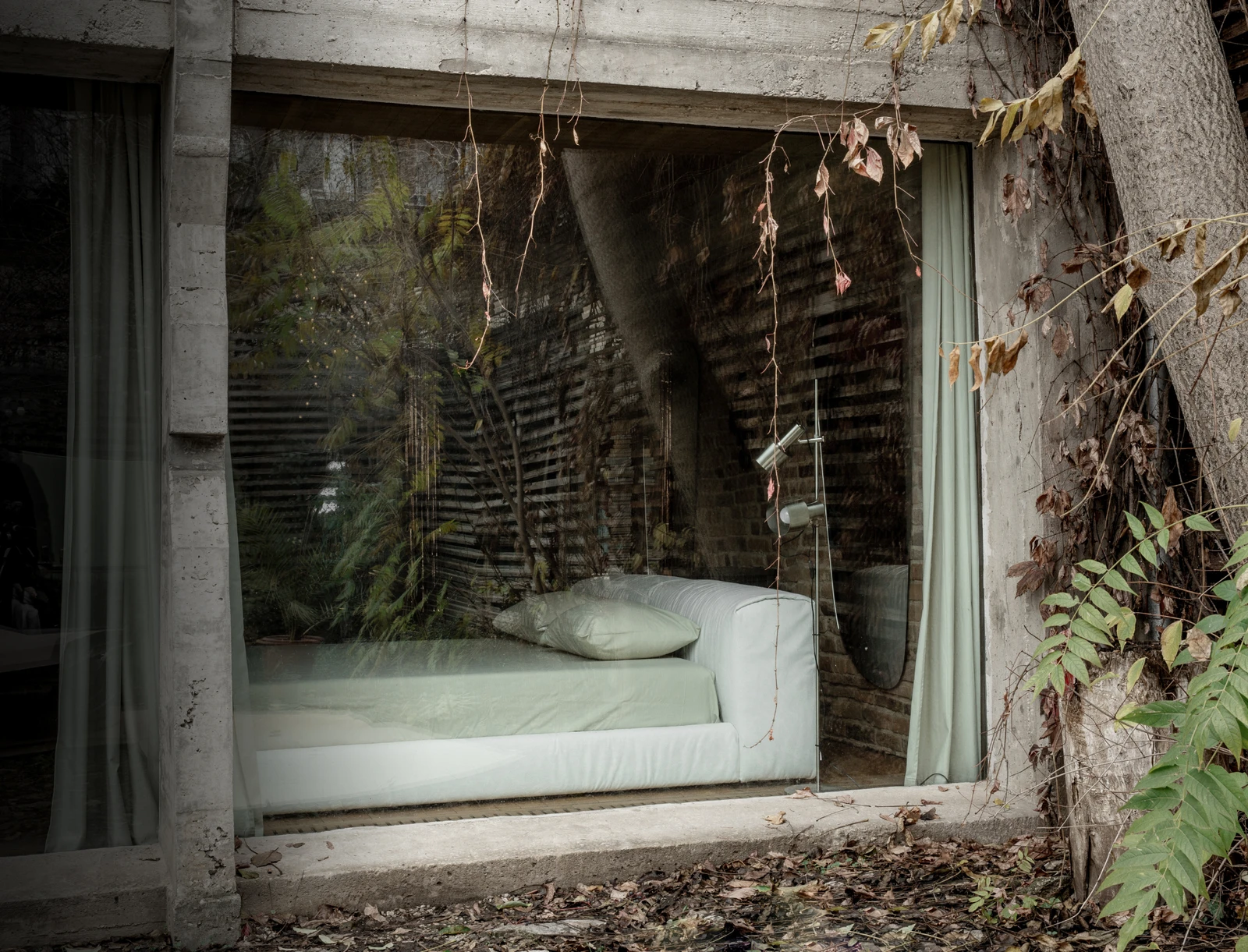 Cream Marmaris seen through a large window of a rustic brick loft with vines and leaves in the foreground