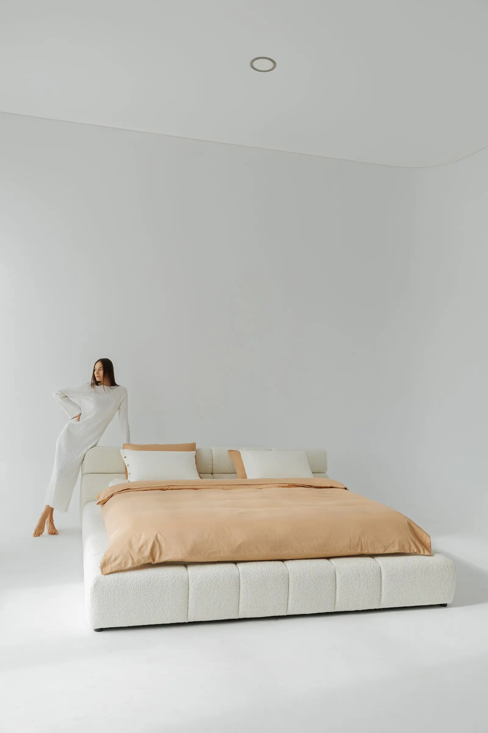 Cream boucle Nao with a model leaning into the headboard pillow