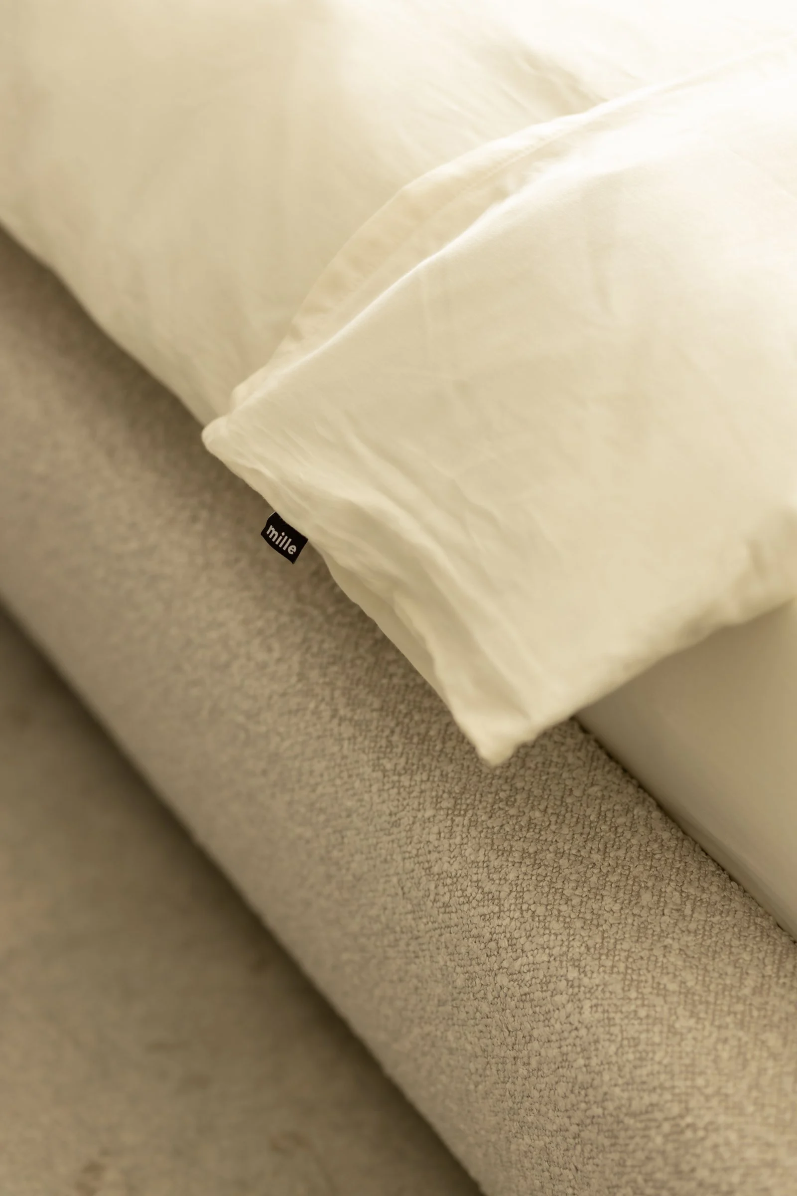 Close detail of the small black Mille label sewn into the boucle seam of the Belagio bed