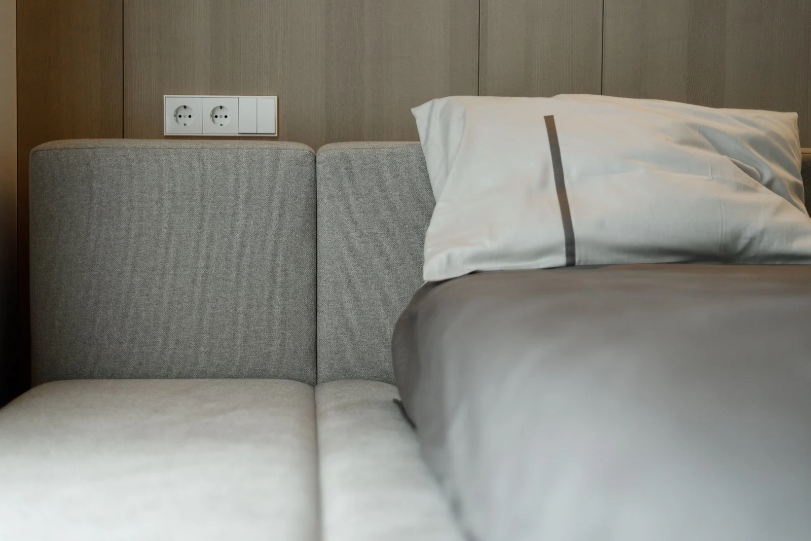 Close detail of the Connect back-cushion modules meeting the wood-paneled wall, electrical outlets and bench platform visible