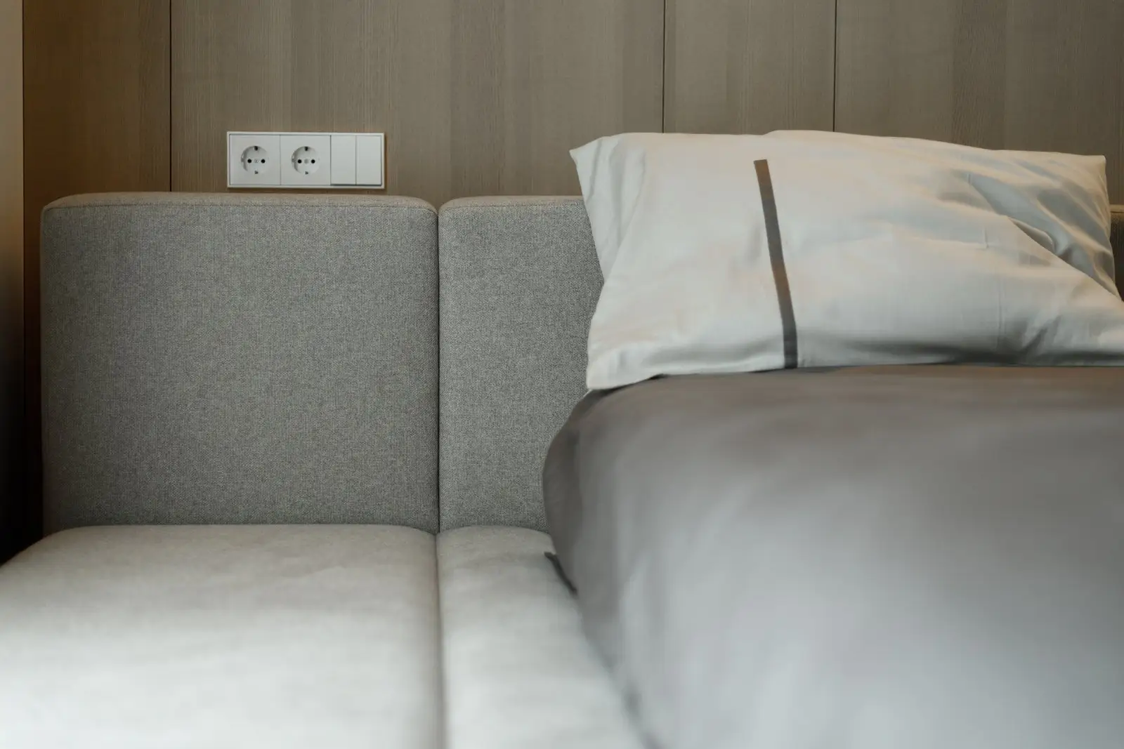 Detail of the Connect back-cushion sectional with electrical outlets mounted in the wood-paneled wall behind