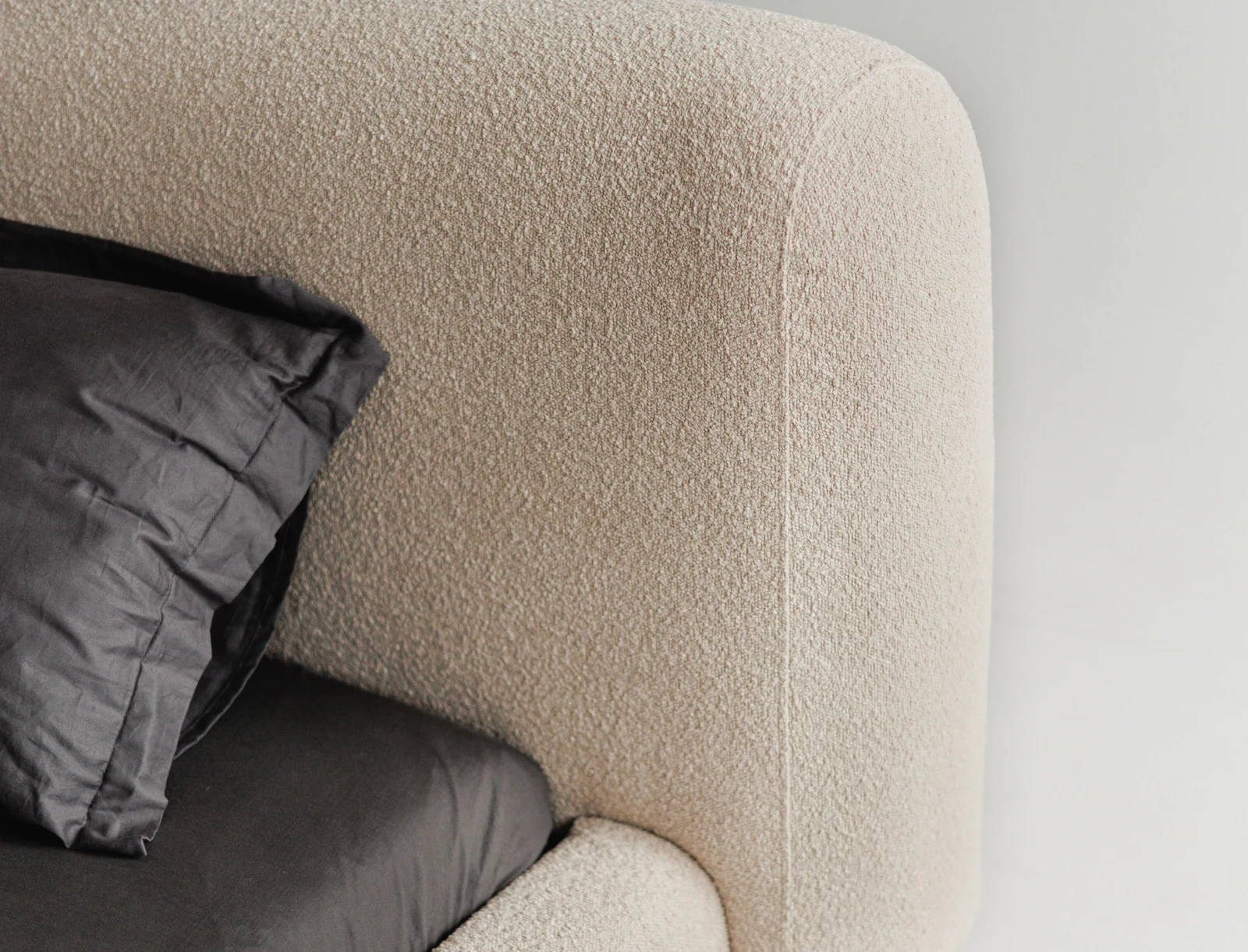 Macro of the Fresco headboard corner showing the sand boucle weave curving into the rounded top edge