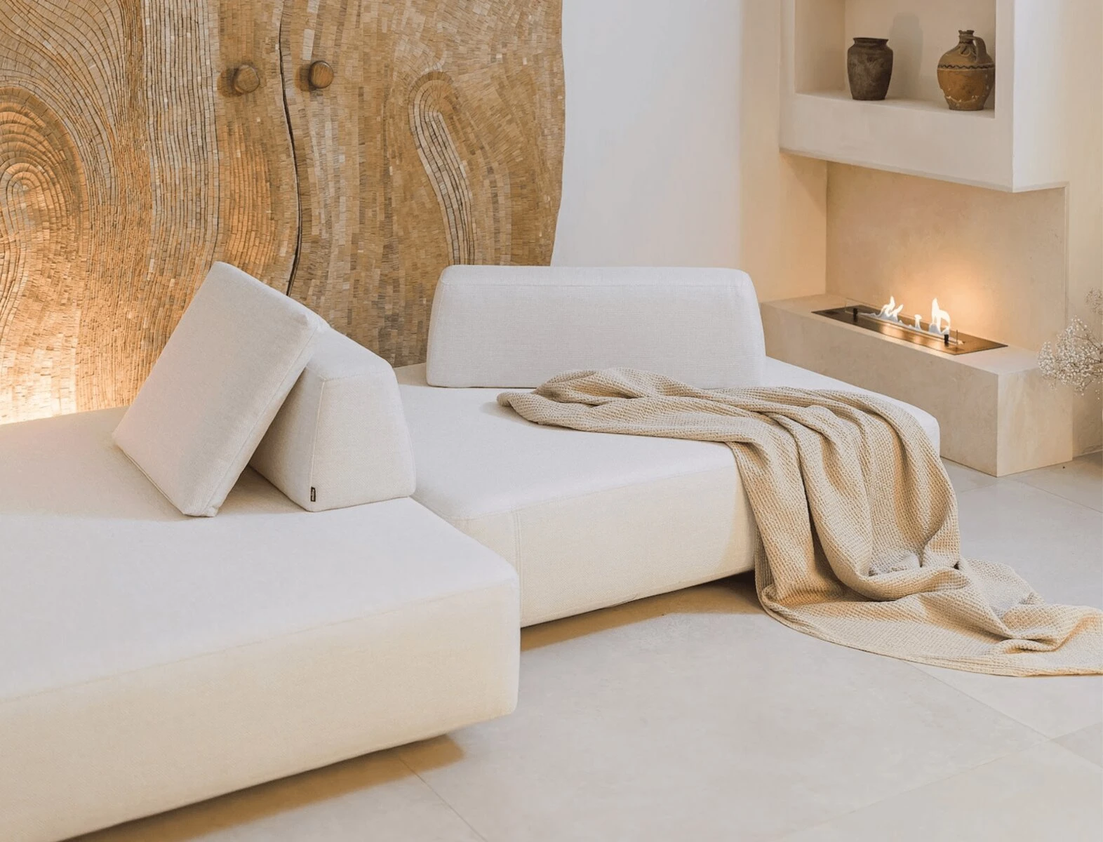 Cream Deseda in a studio with a wood-grain feature wall, a fire bowl and a knitted throw