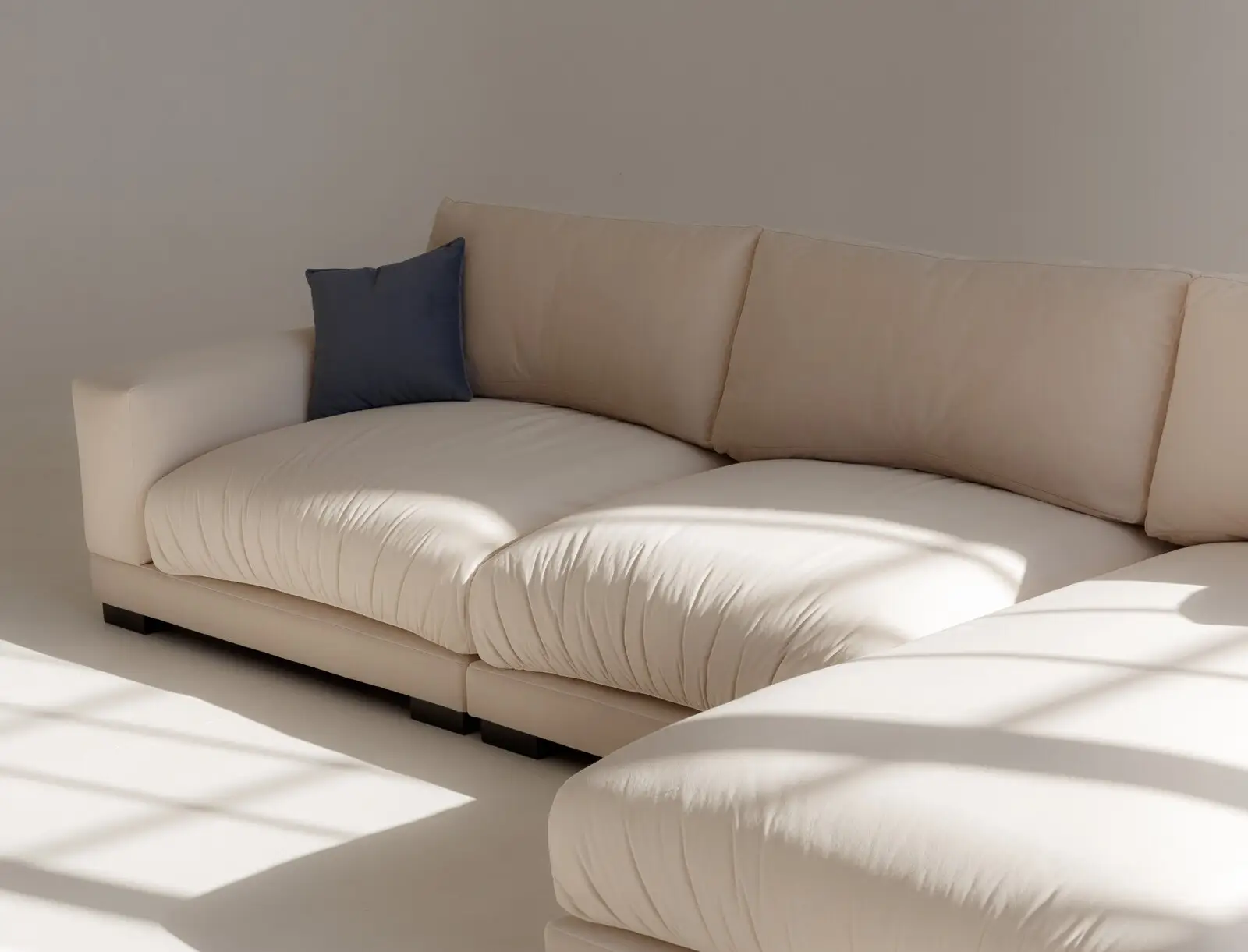 Cream Palermo seat detail with a small navy throw pillow and slanted daylight