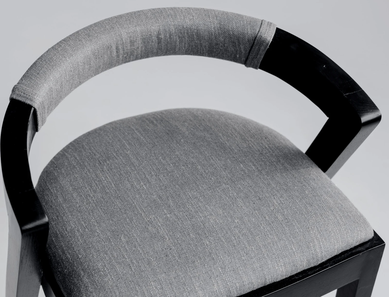 Three-quarter view of the Baffi bar stool showing the black-stained ash sawhorse frame and the round upholstered seat