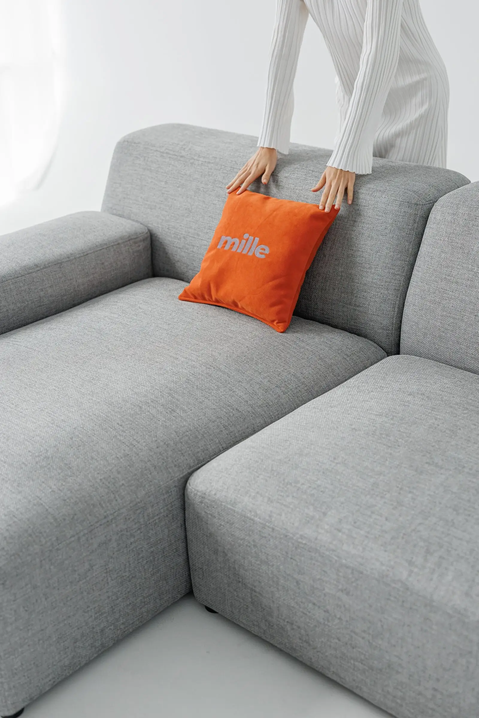Model placing a Mille pillow on a grey Kingston