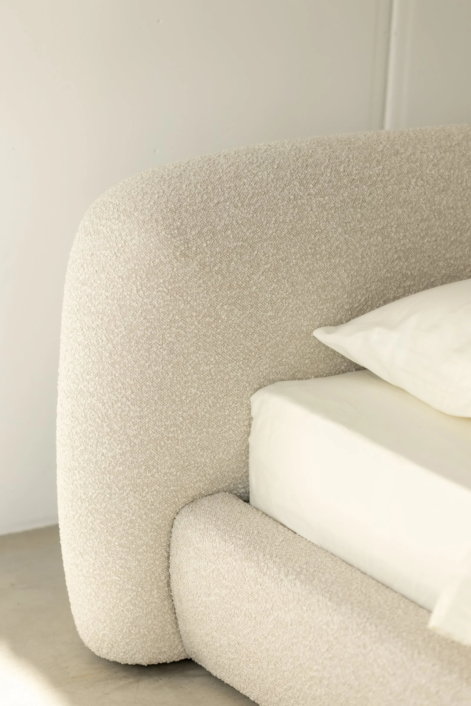 Side detail of the Belagio headboard meeting the bed frame in one continuous soft curve