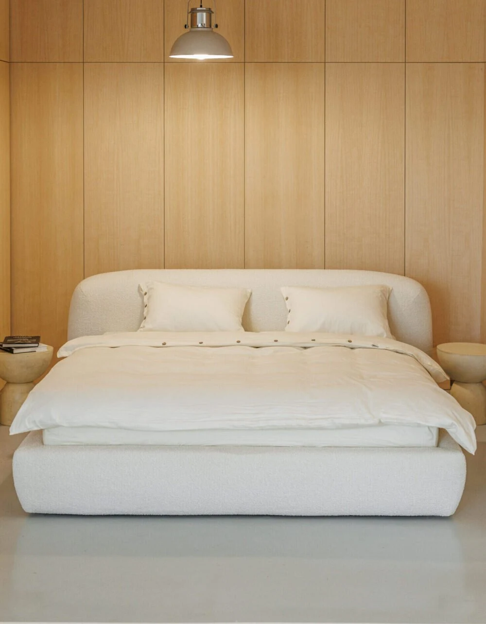 Cream boucle Belagio centered in a warm wood-paneled bedroom under a single industrial pendant lamp