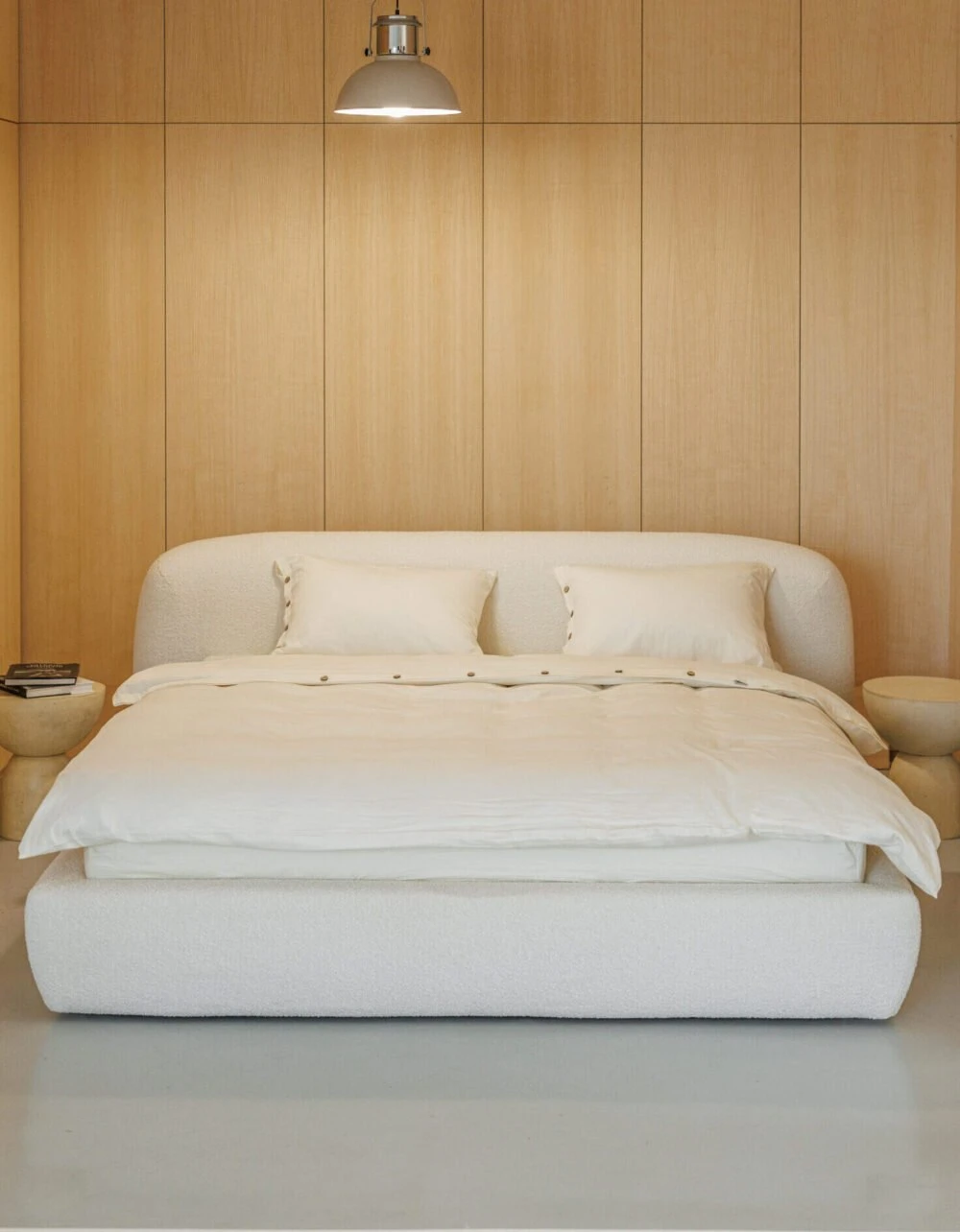 Cream boucle Belagio centered in a warm wood-paneled bedroom under a single industrial pendant lamp