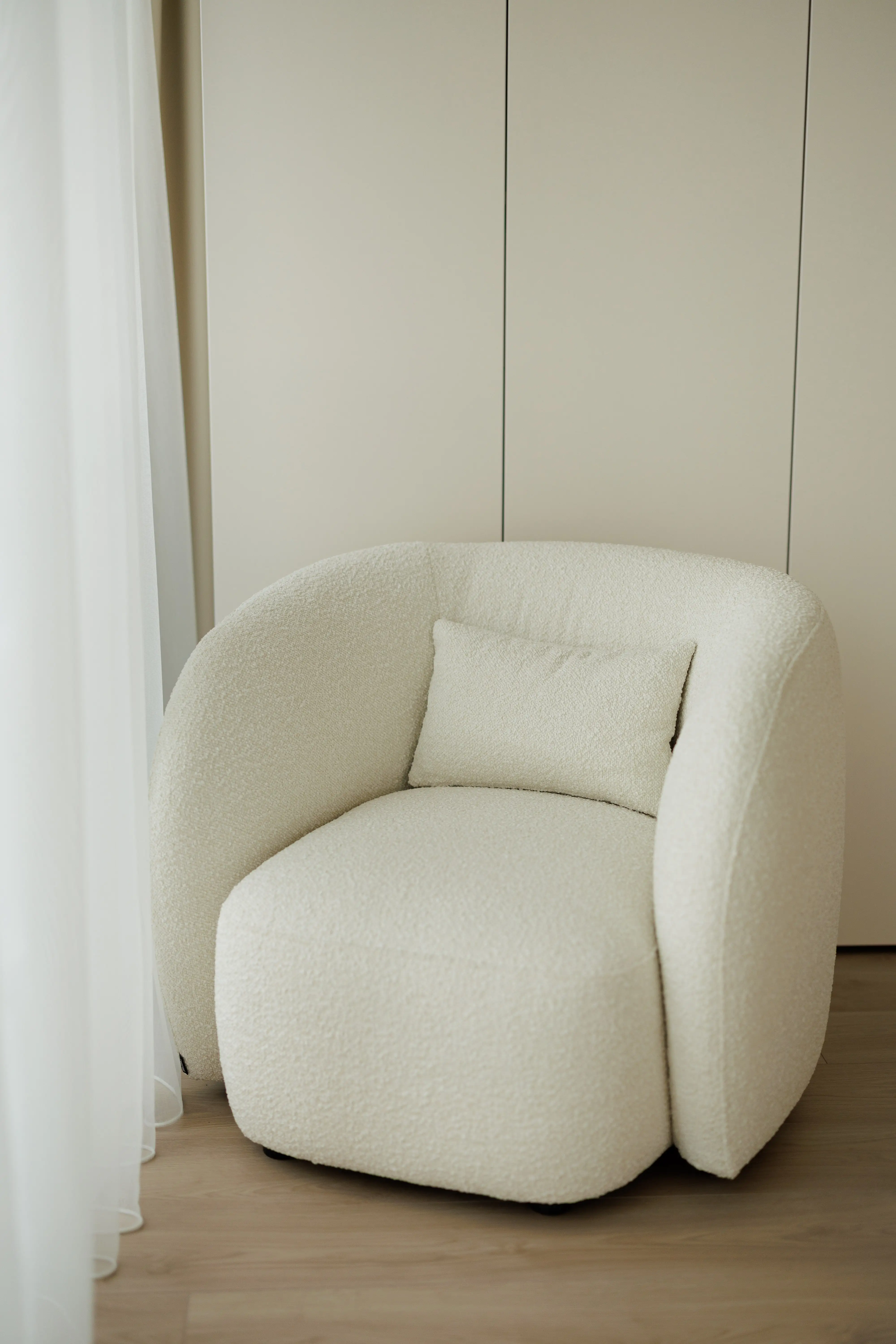 Cream boucle Nuba armchair in an apartment by a sheer white curtain