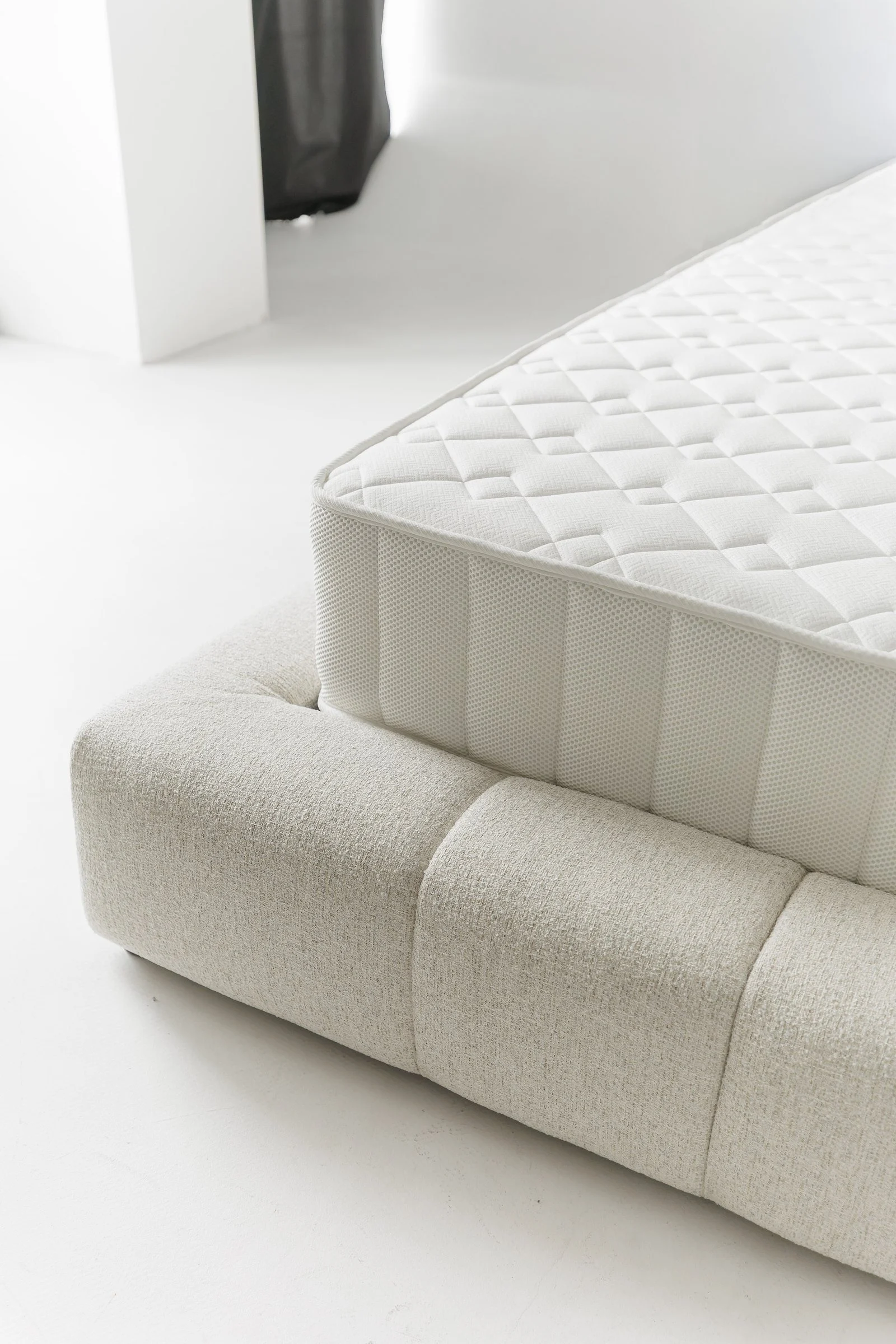 Close detail of a Mille-branded mattress edge resting on the Nao's channelled base