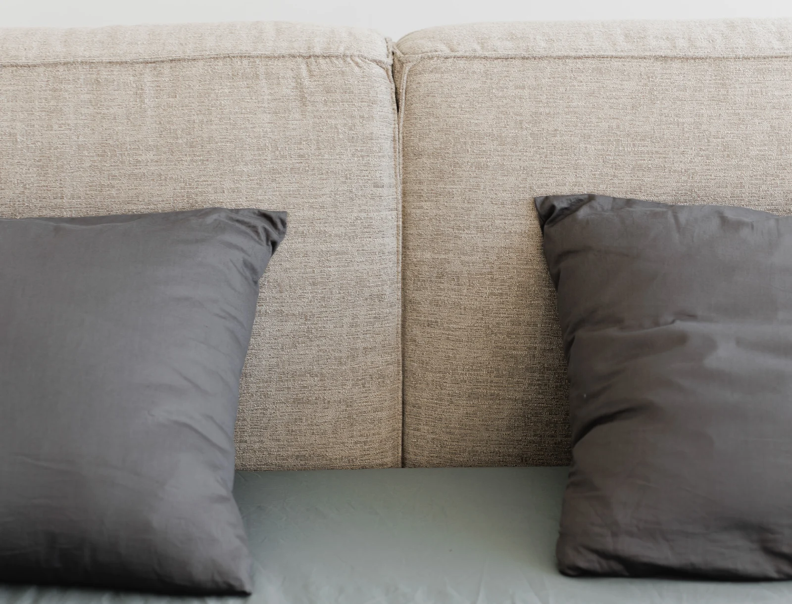 Macro of two grey pillows resting in front of two sand cushion blocks, the modular seam visible between them