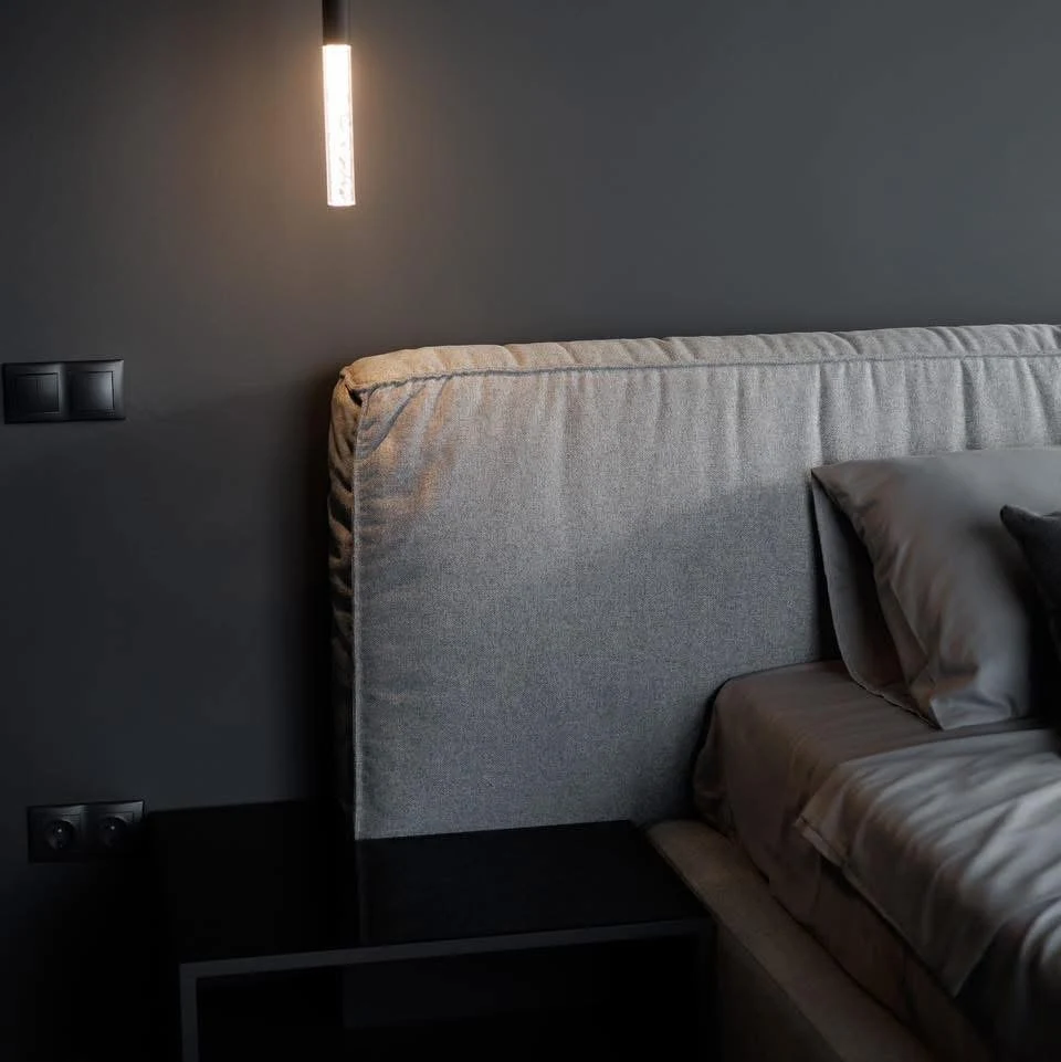 Close detail of the Palermo headboard showing the vertical seam where the two grey cushion blocks meet, hanging tube pendant lit above