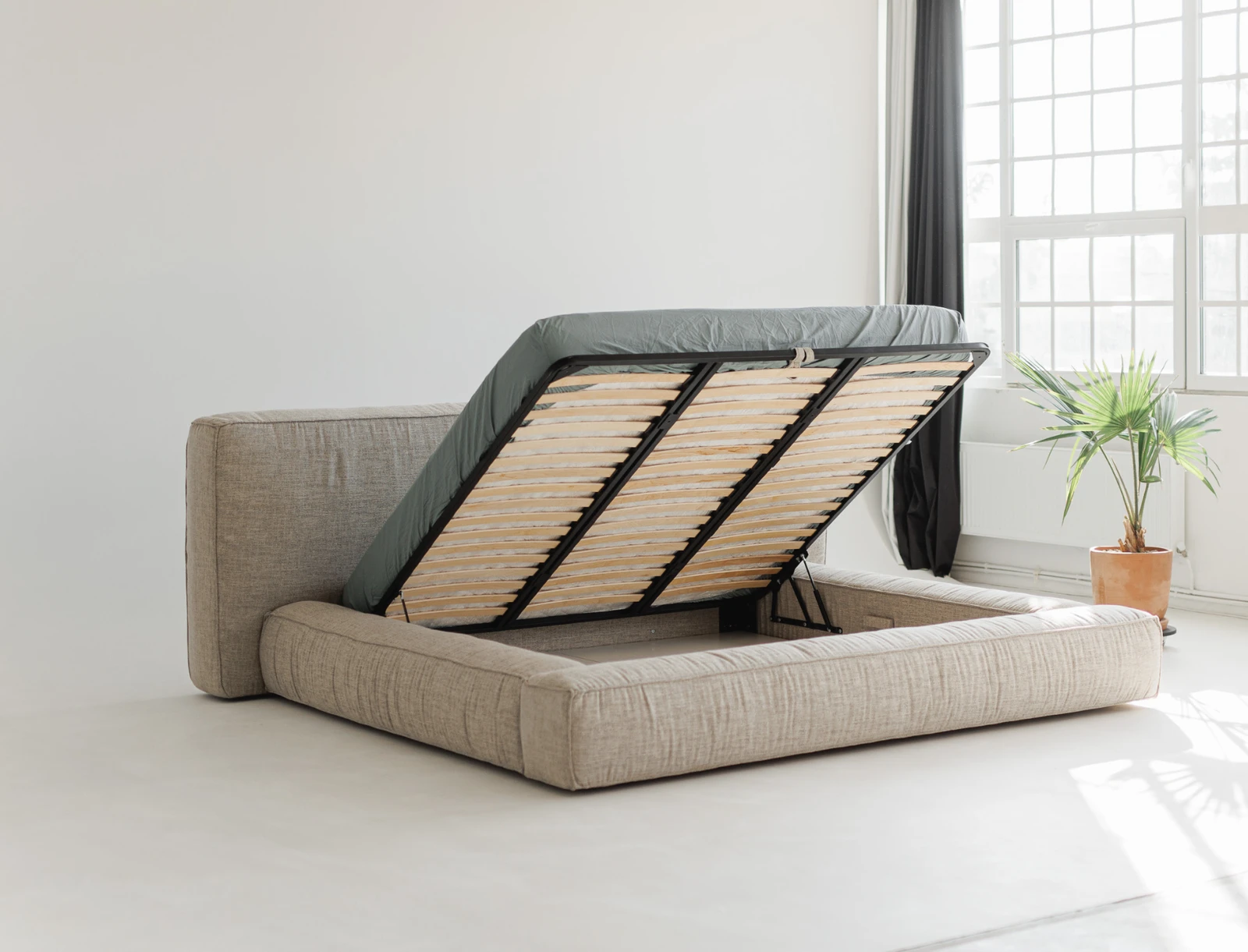 Palermo with the gas-lift base raised at 45 degrees, slatted wood platform visible, plant by the window