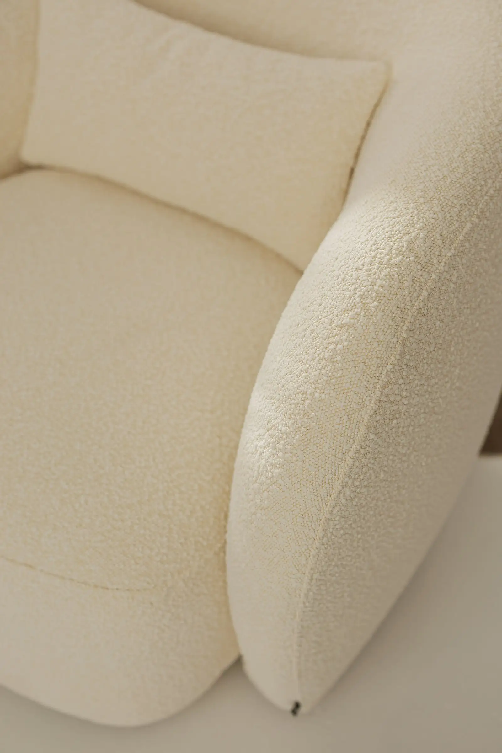 Side angle of the white boucle Nuba armchair showing the wraparound back form